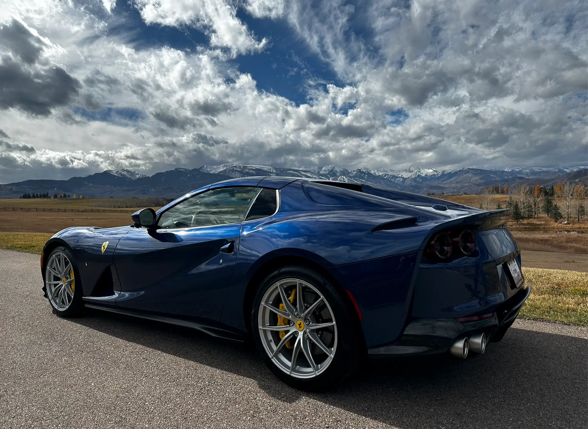 Blue Ferrari 812 on a private drive with the snow-capped Elk Mountains beyond