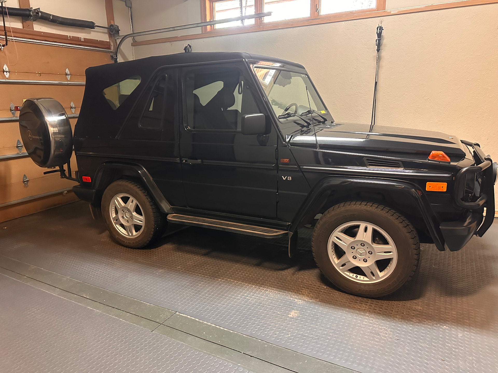 A black Mercedes-Benz G500 cabriolet stored in a private garage