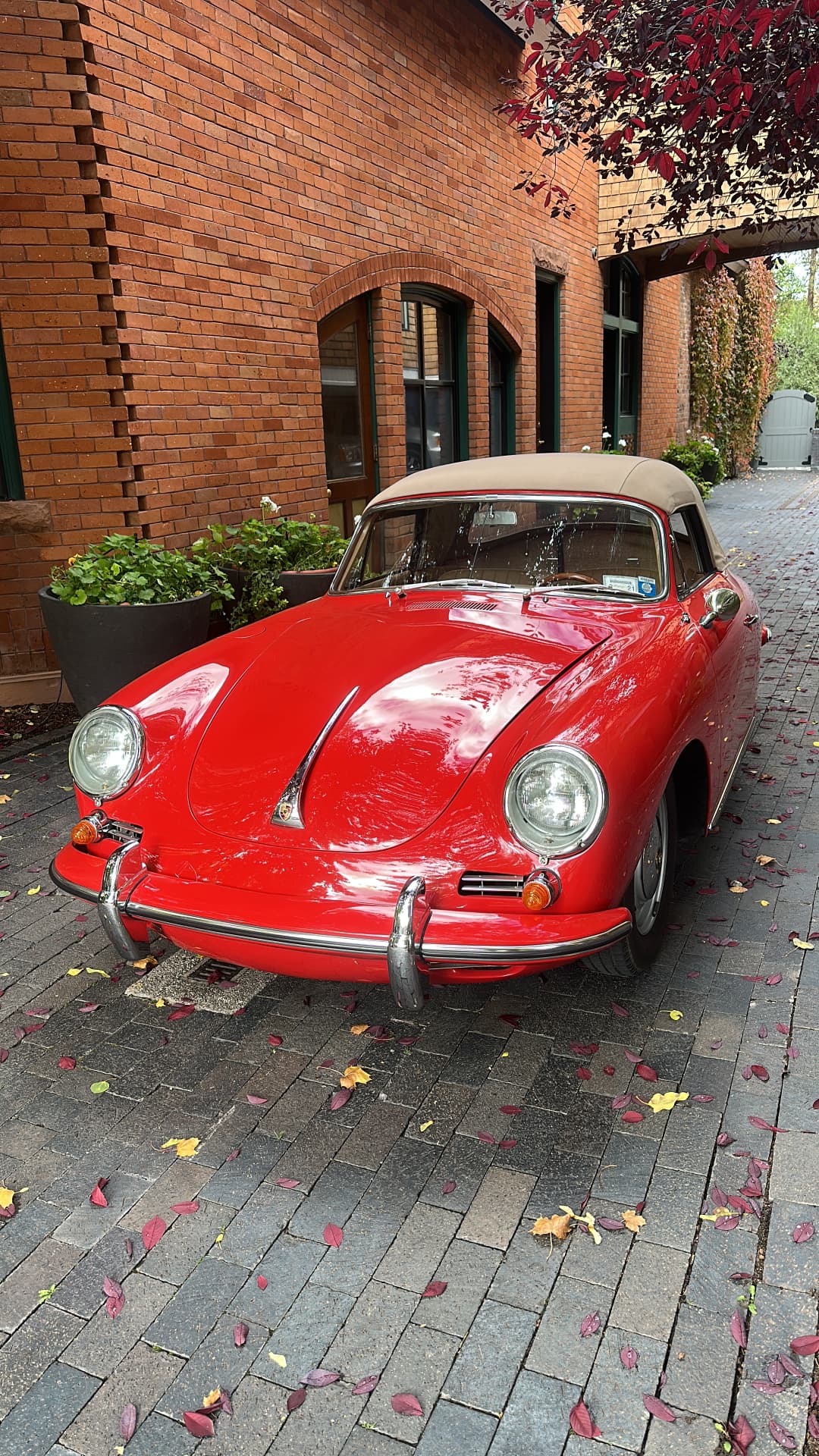 A red vintage Porsche 356 cabriolet on a brick drive in autumn