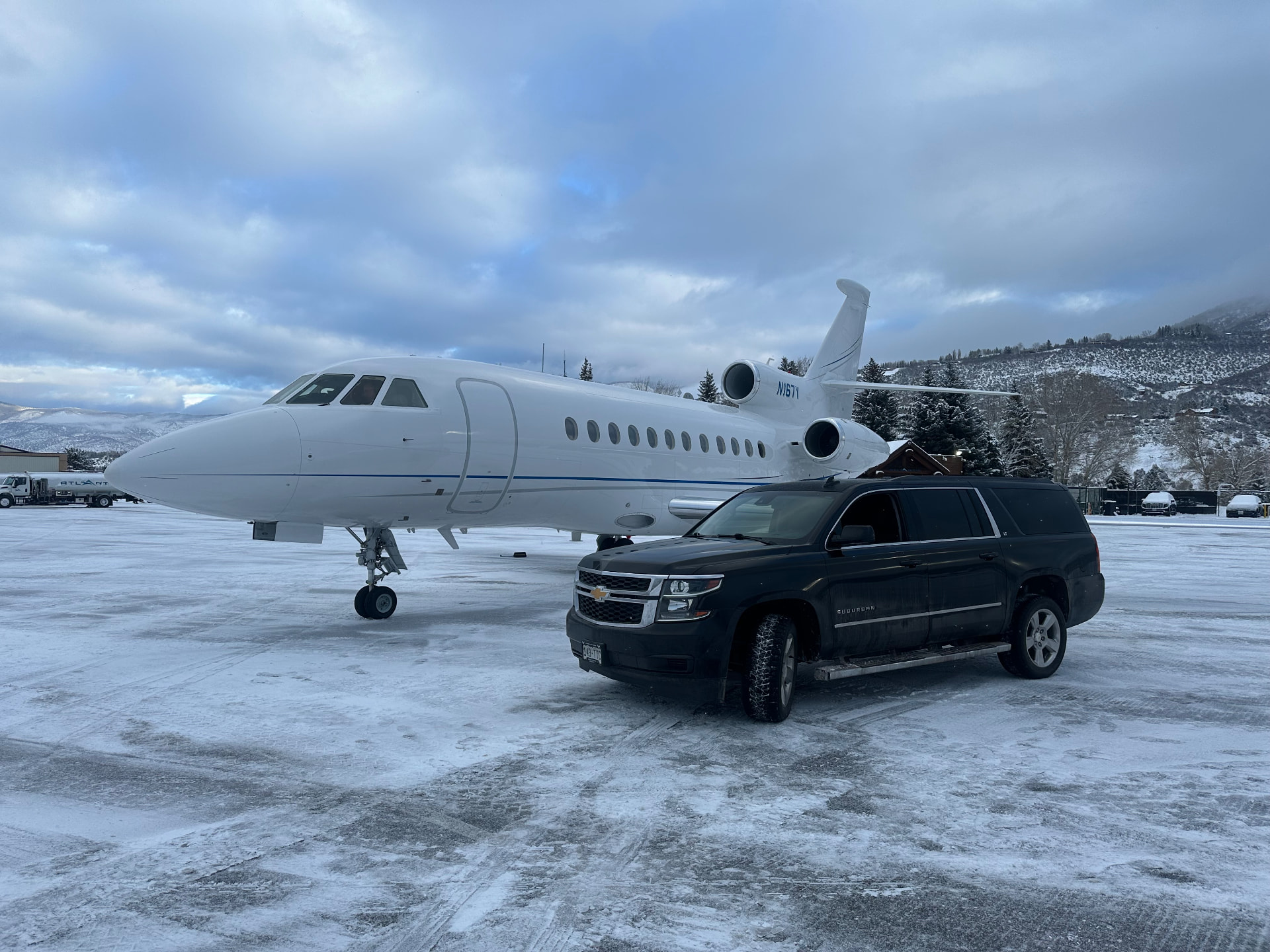 A private jet and black SUV waiting on a snowy Aspen tarmac