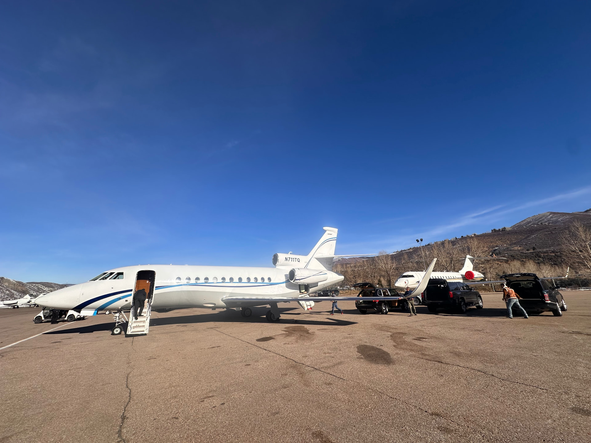 Multiple private jets on the Aspen tarmac with ground transport ready