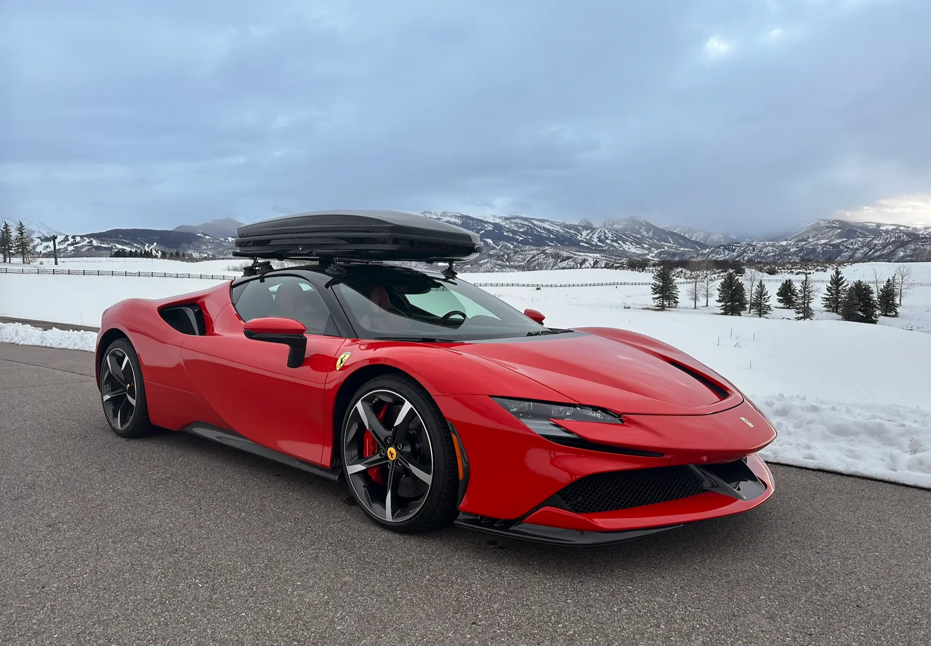 Red Ferrari SF90 with a roof box, prepared for winter driving against the snow-covered Roaring Fork Valley